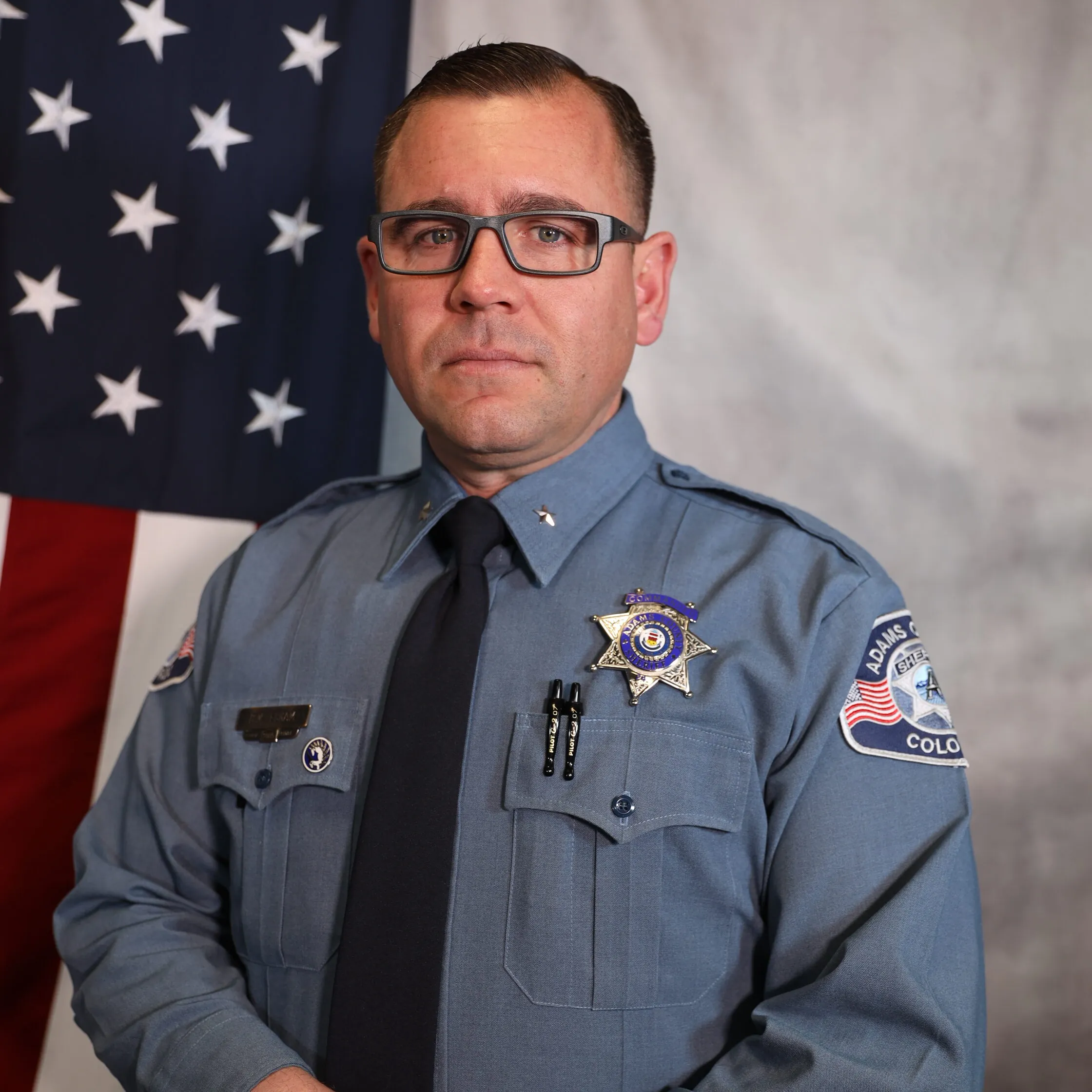 Brett Eskam posing in uniform with U.S. flag
