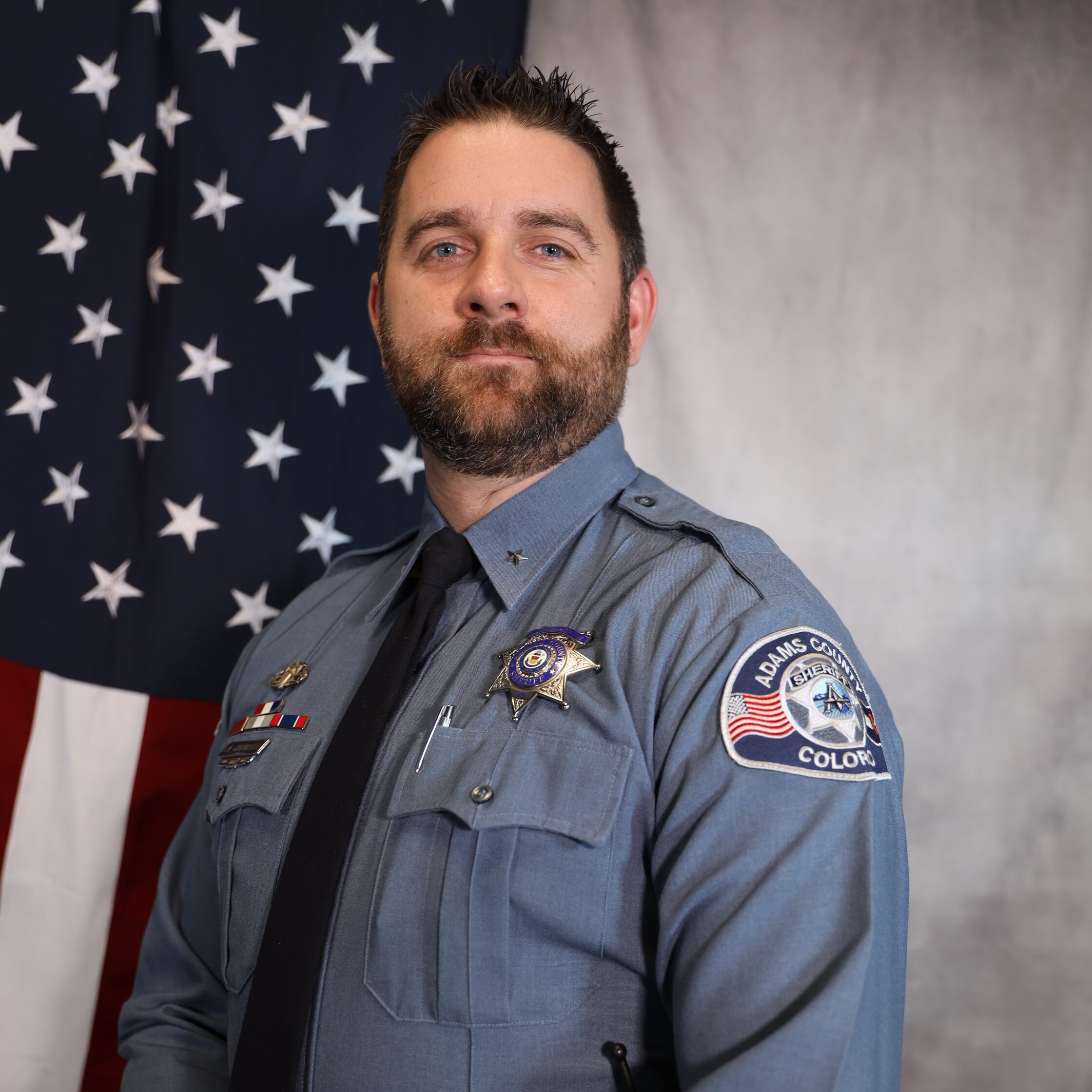 Gruenberger, Christopher in sheriff uniform with U.S. flag backdrop