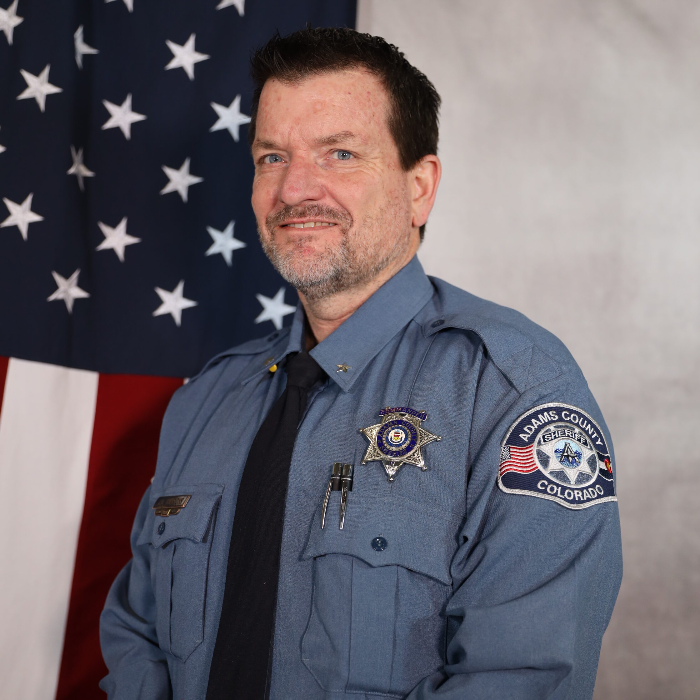 Jim Hinrichs staning in front of the U.S. Flag in Uniform