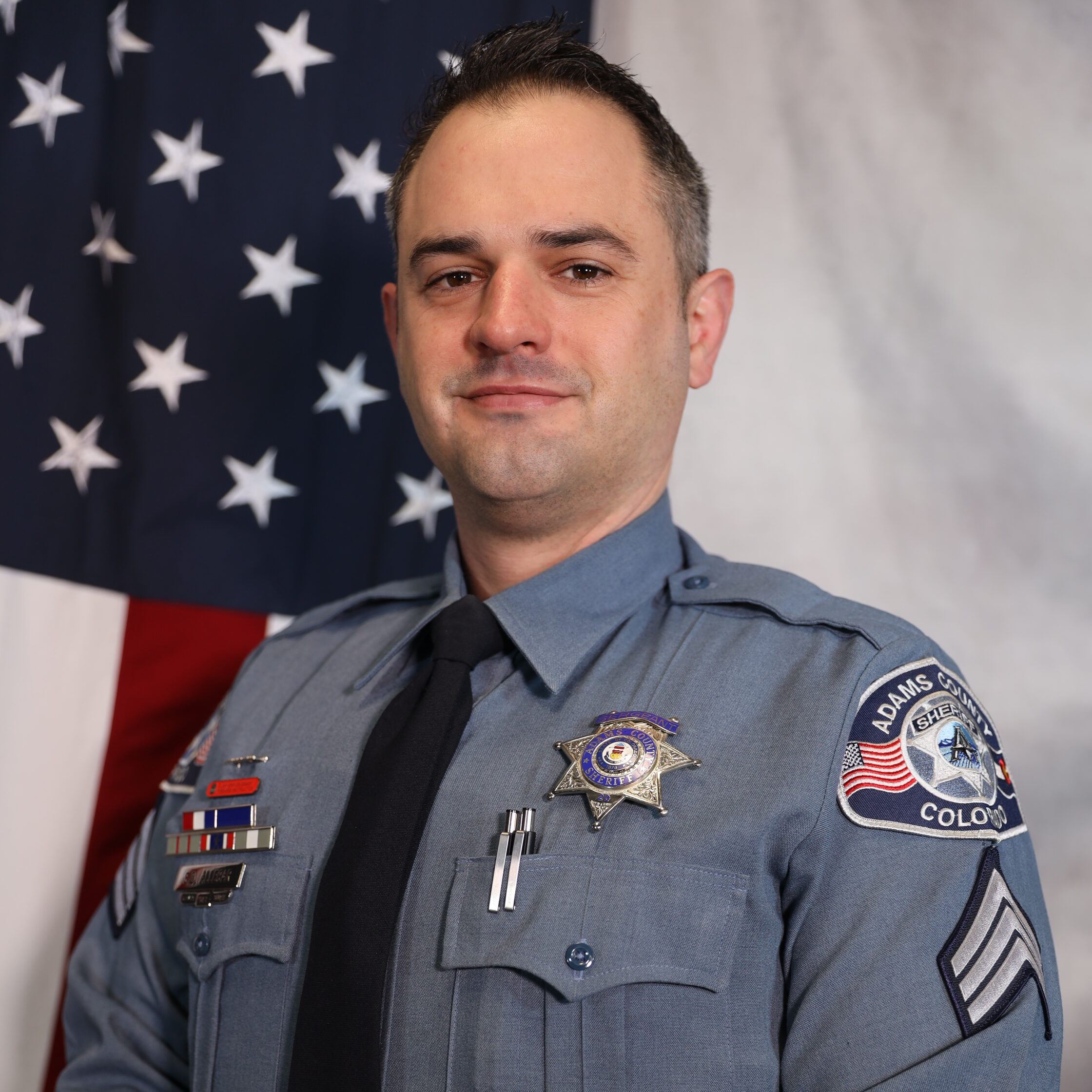 Commander Sean Allegar standing next to American flag in uniform.