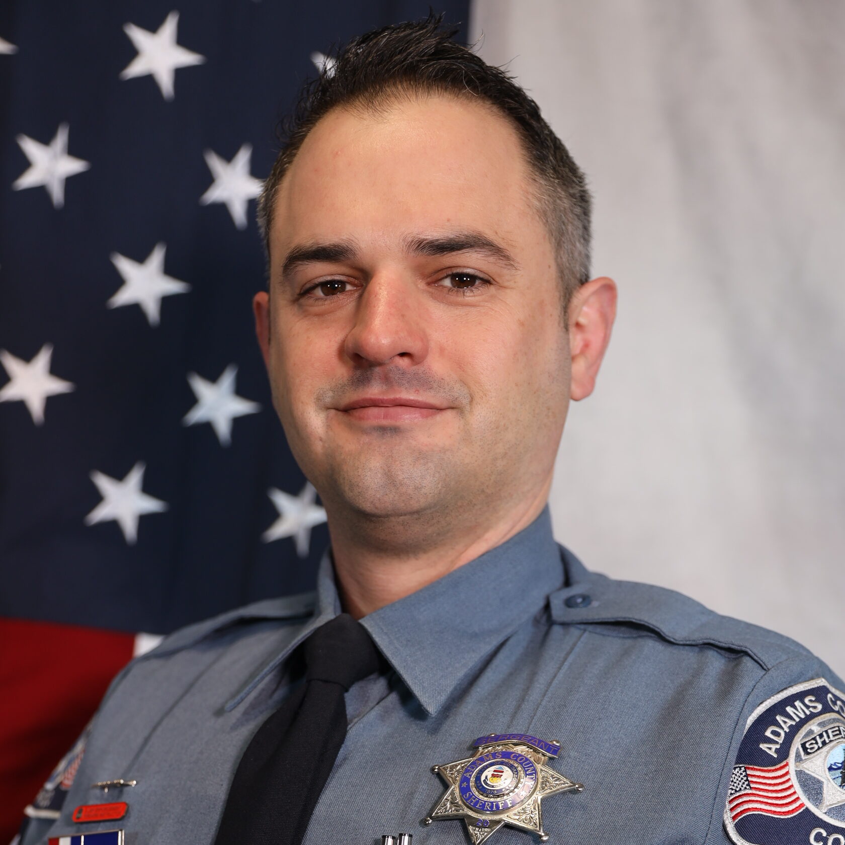 Commander Sean Allegar standing next to American flag in uniform.
