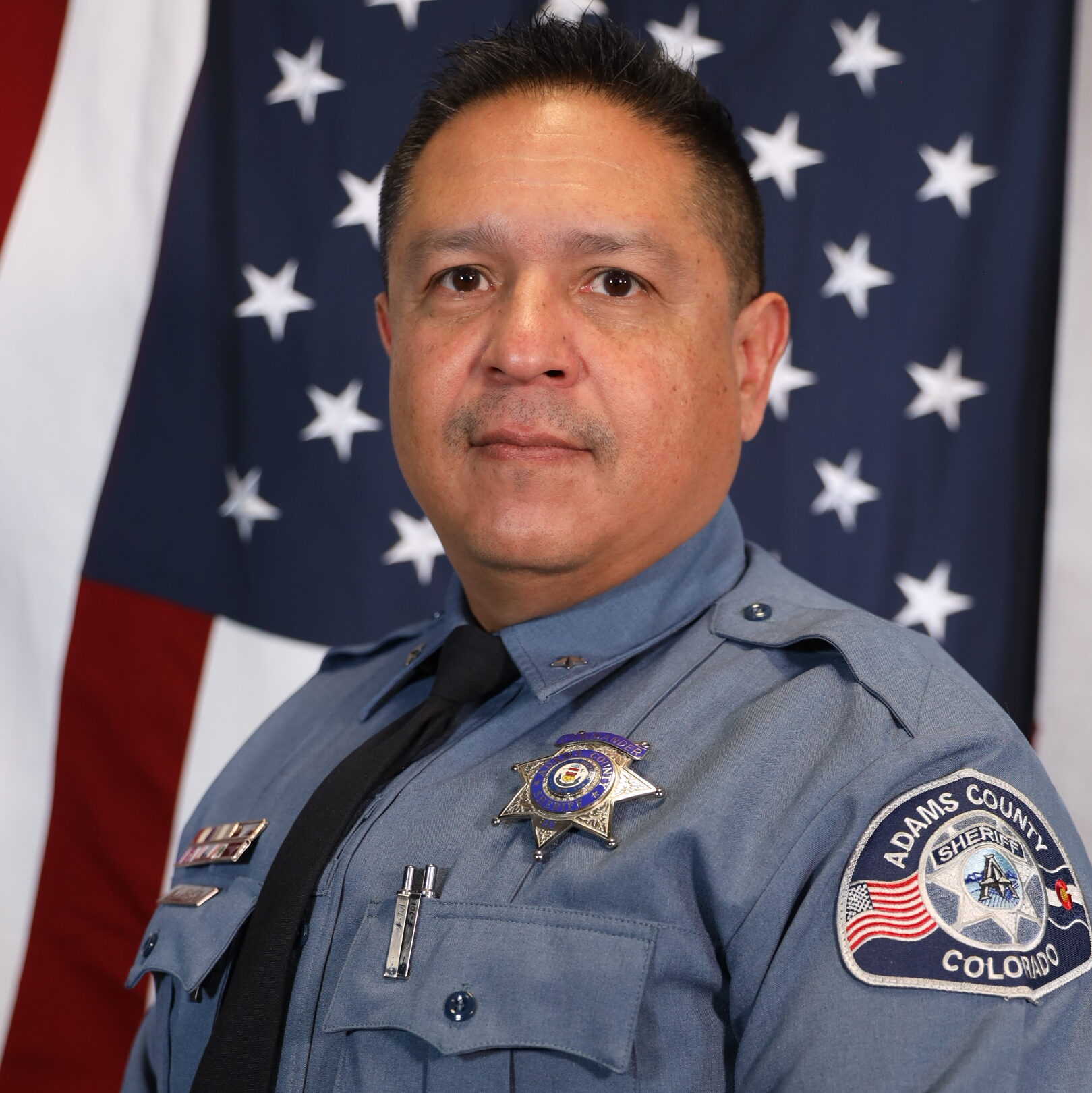 Aragon Manuel in uniform stands before an American flag