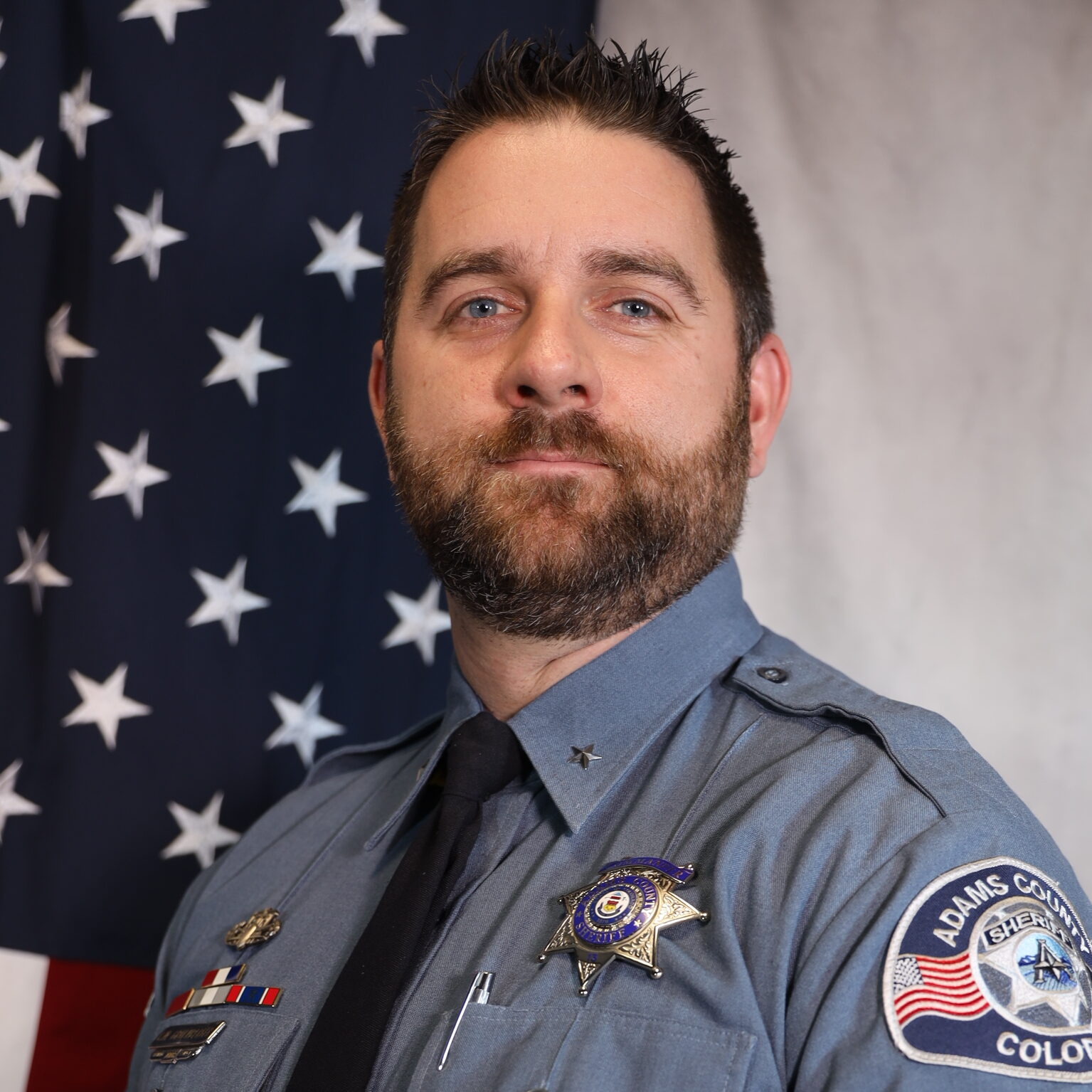 Gruenberger, Christopher in sheriff uniform with U.S. flag backdrop