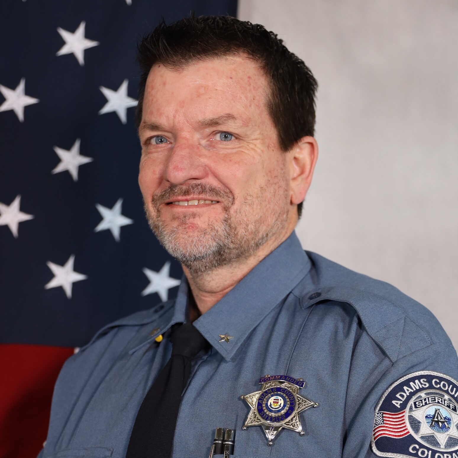 Jim Hinrichs staning in front of the U.S. Flag in Uniform