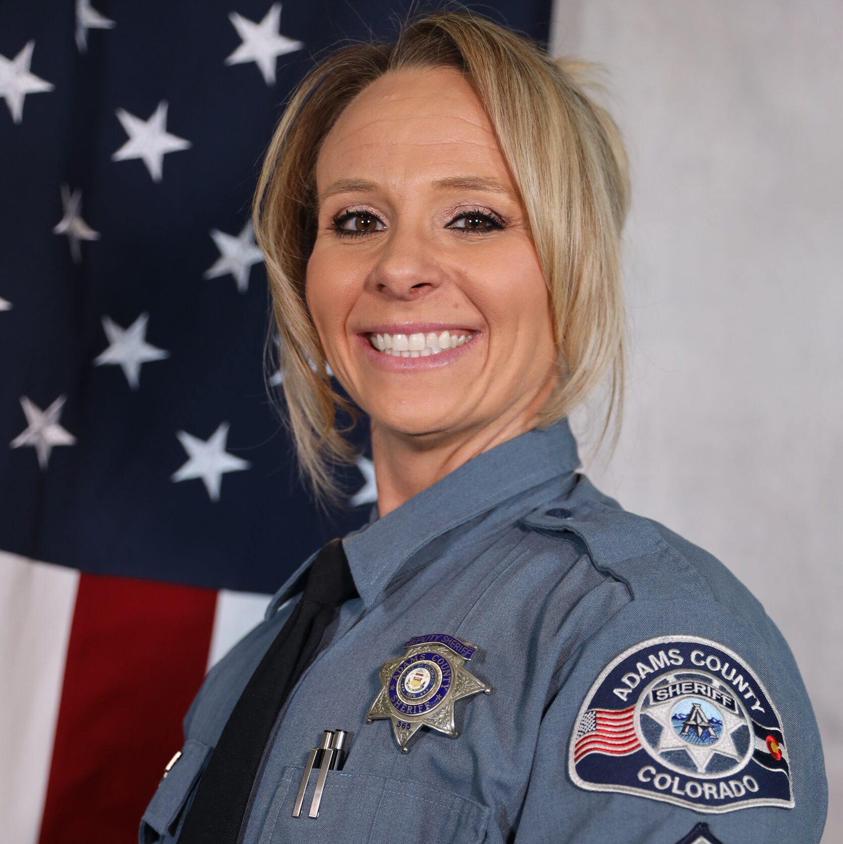 Sarah Titus standing next to American flag in uniform.