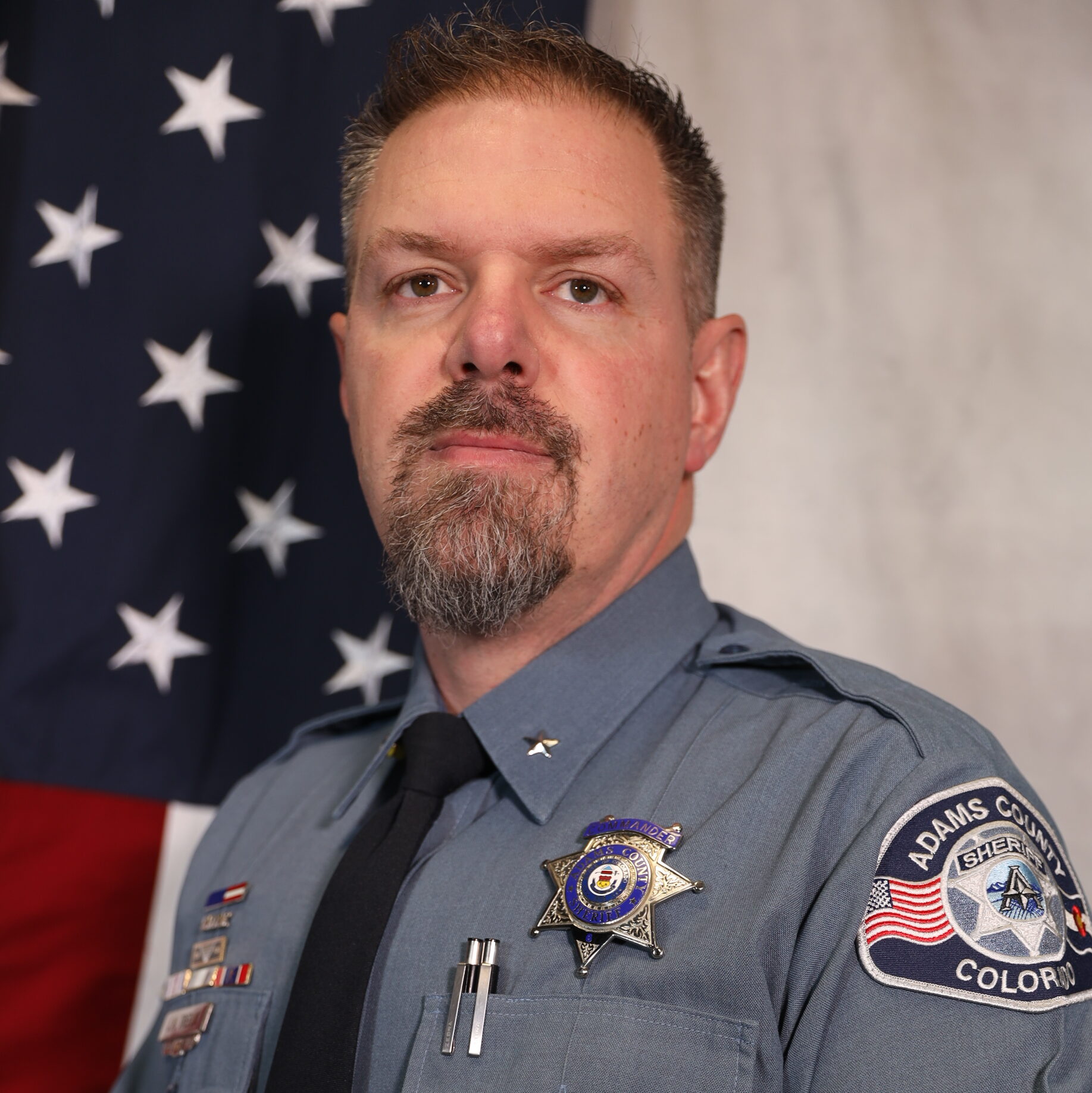 Treblik in uniform against American flag, serious expression