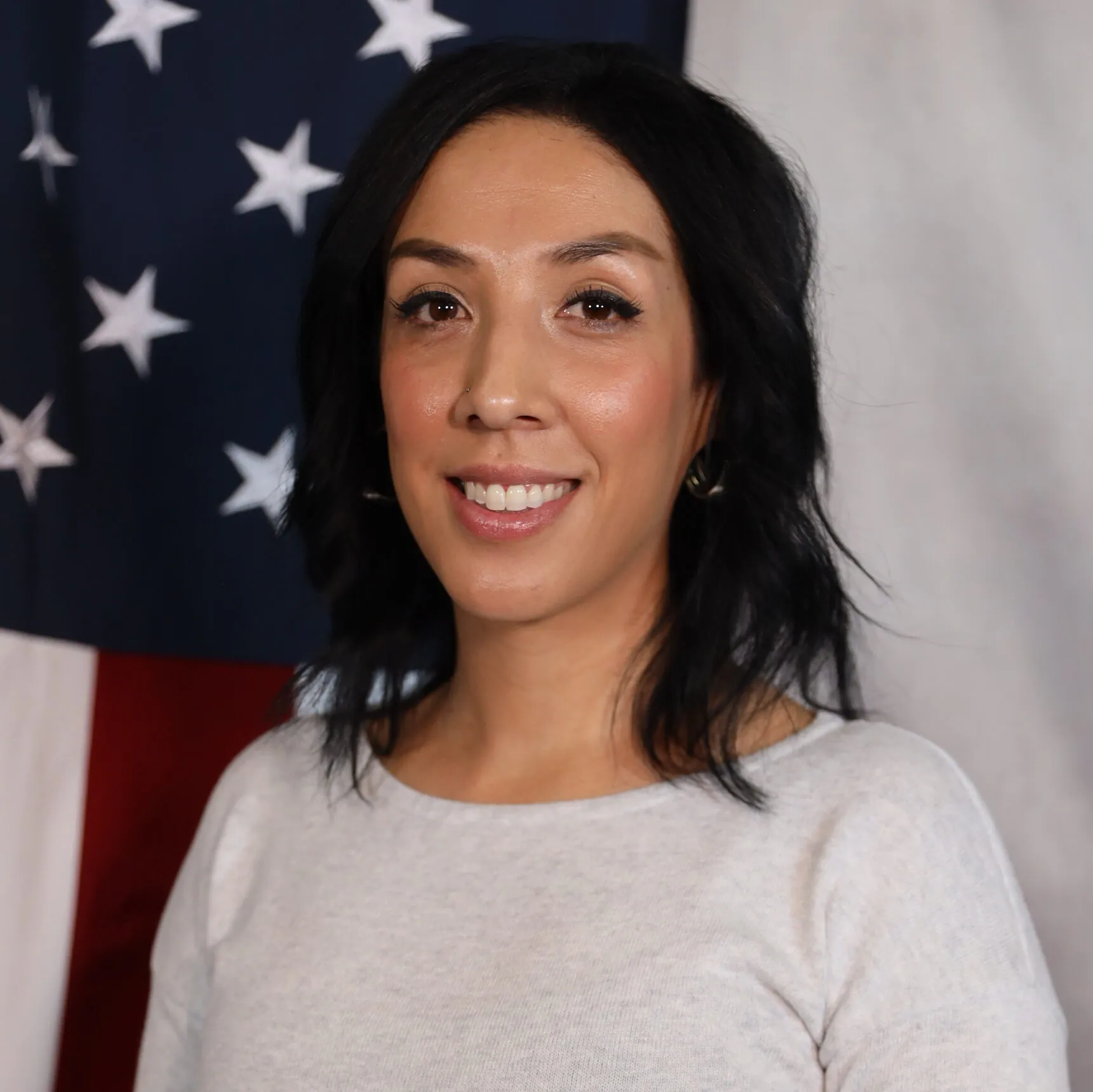 Lexi Wooten smiling in front of an American flag backdrop, representing the Adams County Sheriff’s Office